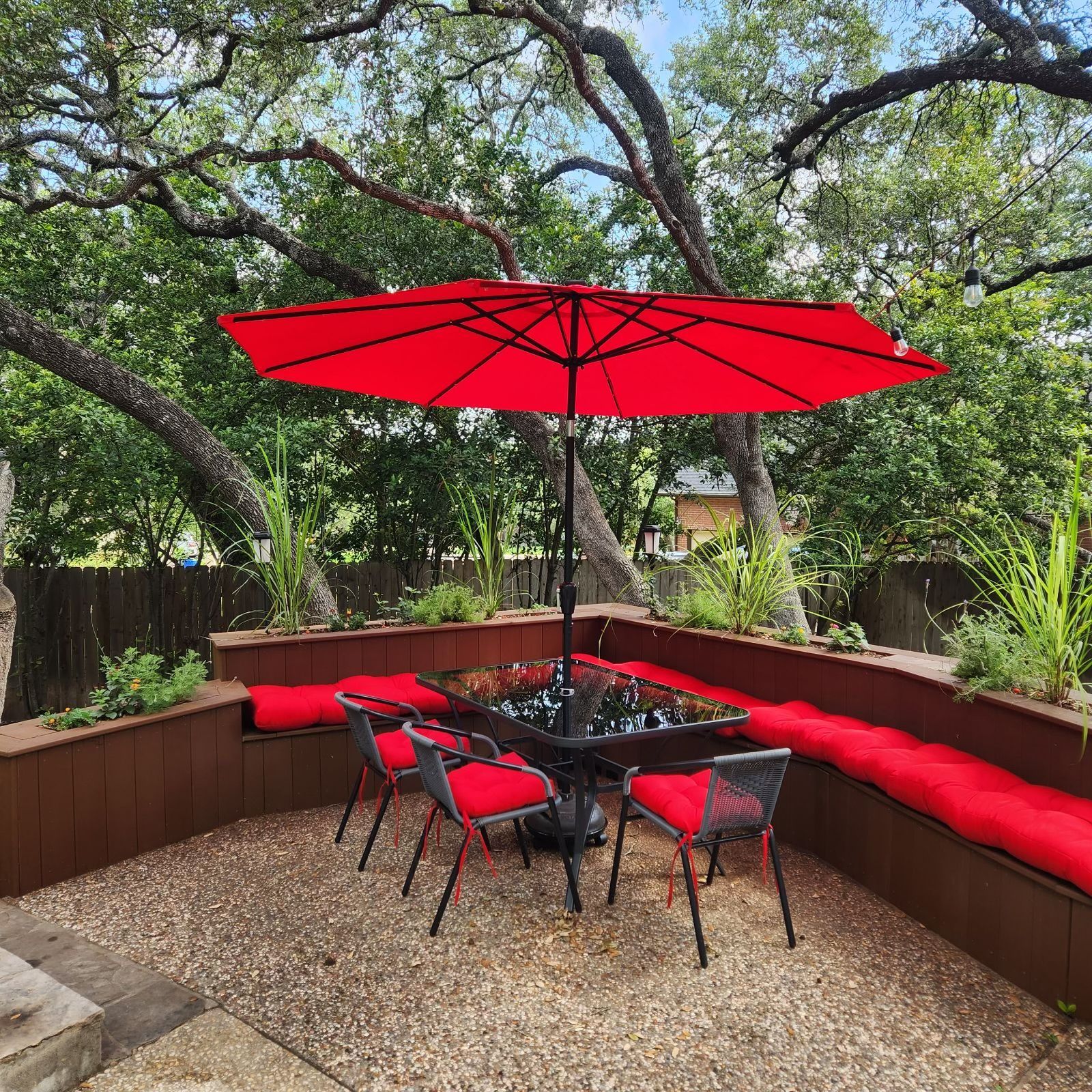 A patio with a table and chairs and a red umbrella.