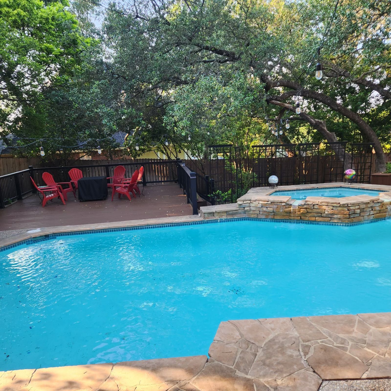 A large swimming pool with a deck and chairs around it.