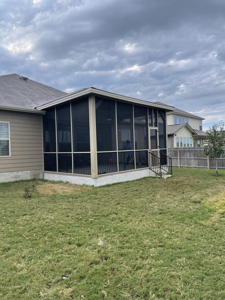 There is a screened in porch in the backyard of a house.