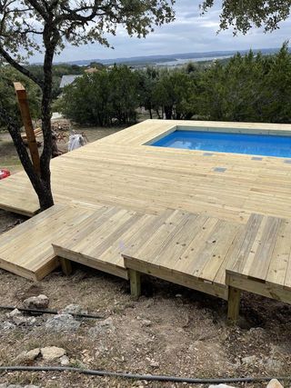 A wooden deck with a swimming pool in the background.