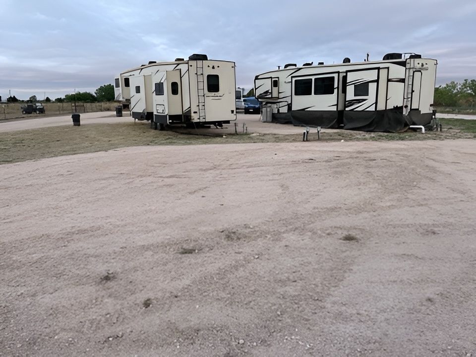 Several RVs parked on a gravel lot under an overcast sky.