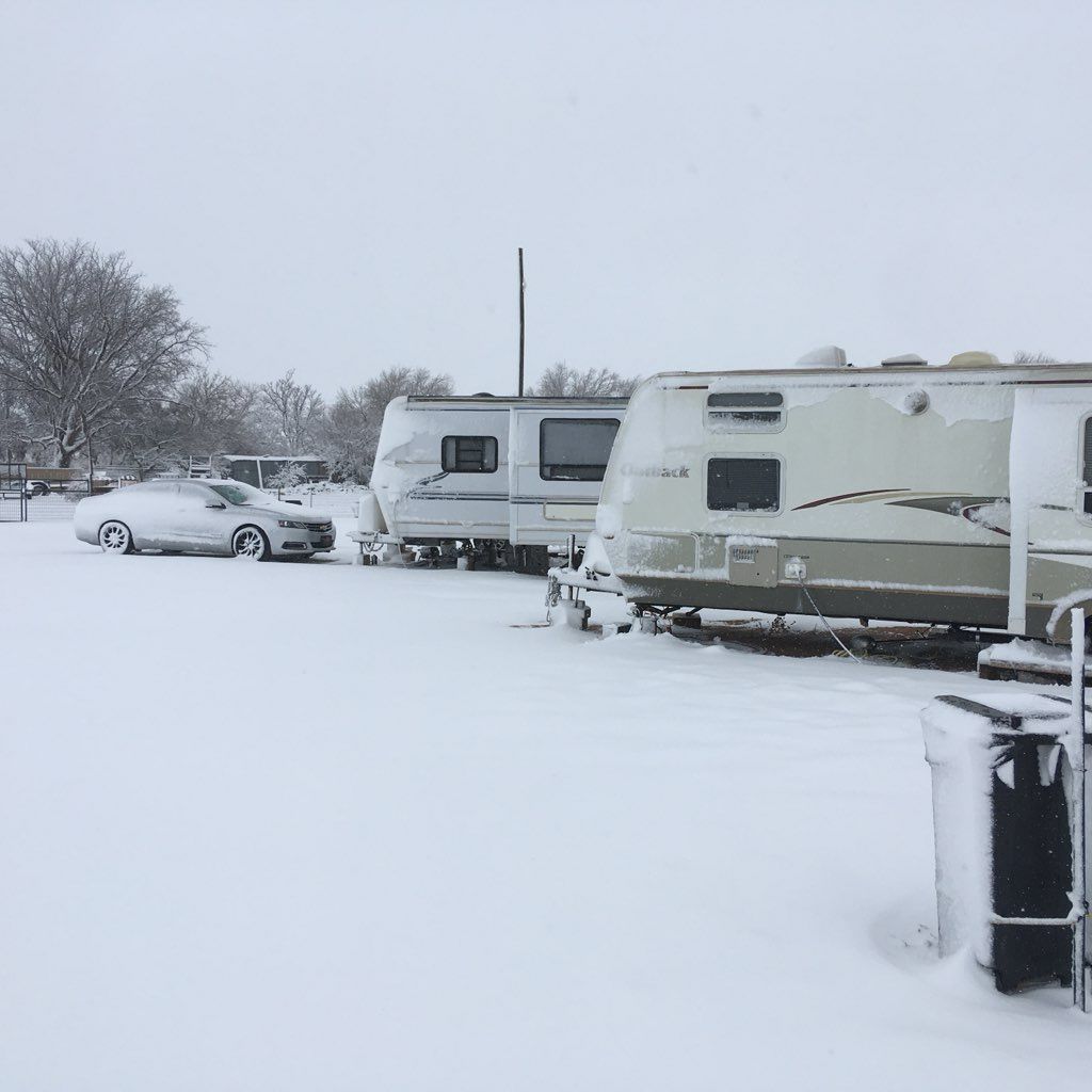 Snowy scene: RVs and a car parked in a snow-covered area.