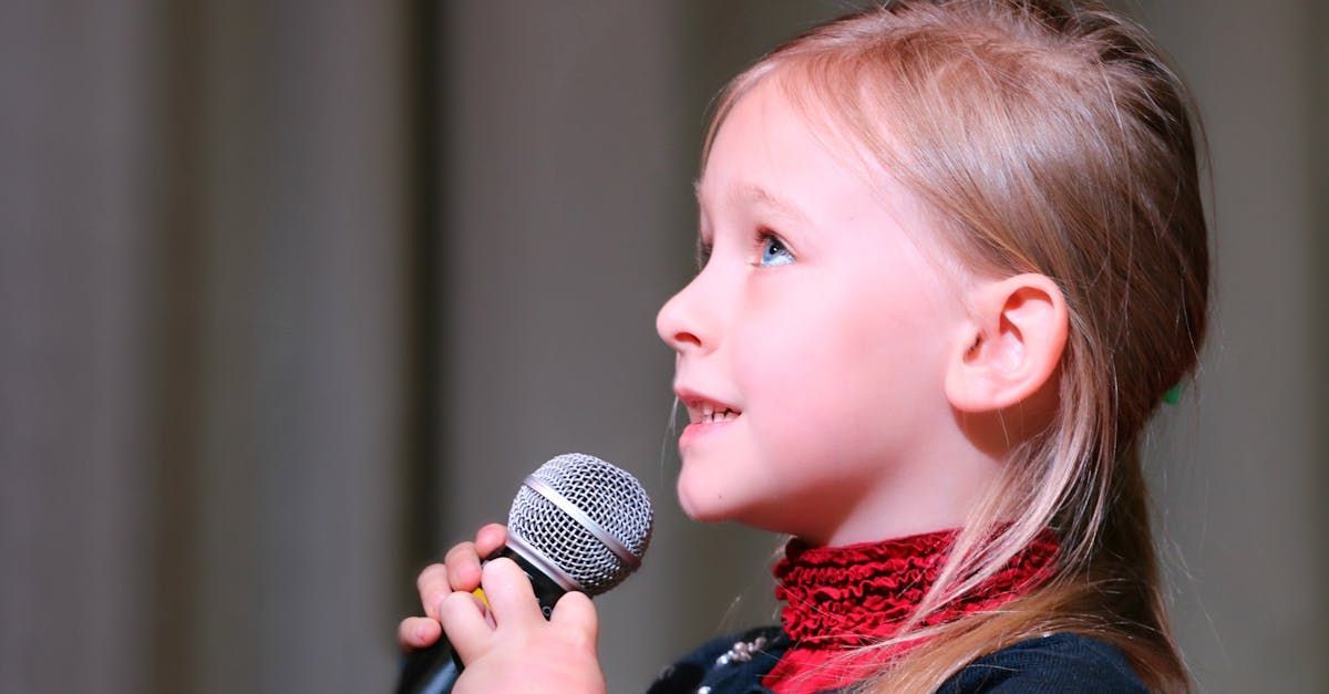 A little girl is singing into a microphone on a stage.