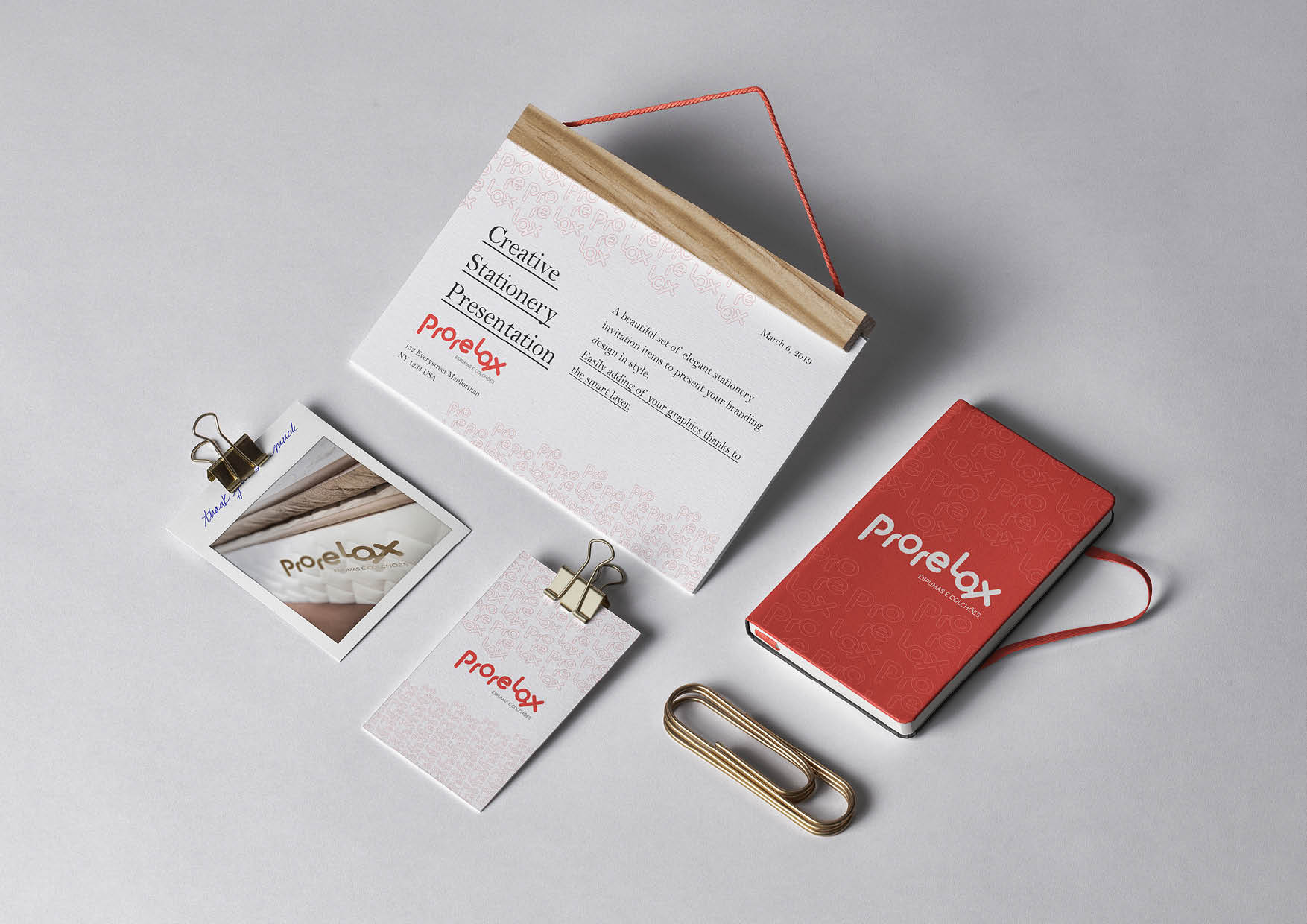 Maquete de papelaria com caderno, calendário e cartões em tons de vermelho, branco e madeira sobre uma superfície branca.