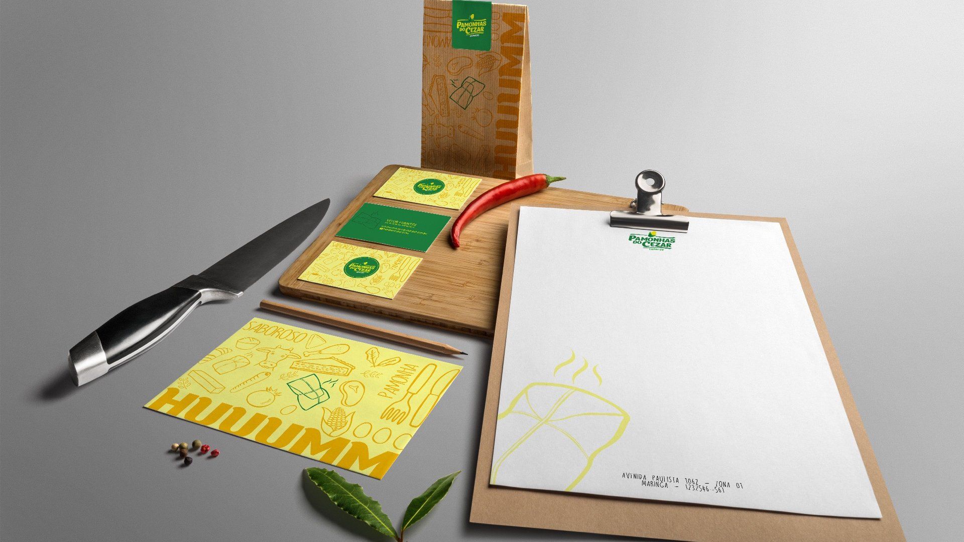 Conjunto de papelaria com tema de papel kraft, apresentando um logotipo, incluindo uma prancheta, um bloco de notas e uma embalagem com uma faca e pimenta.