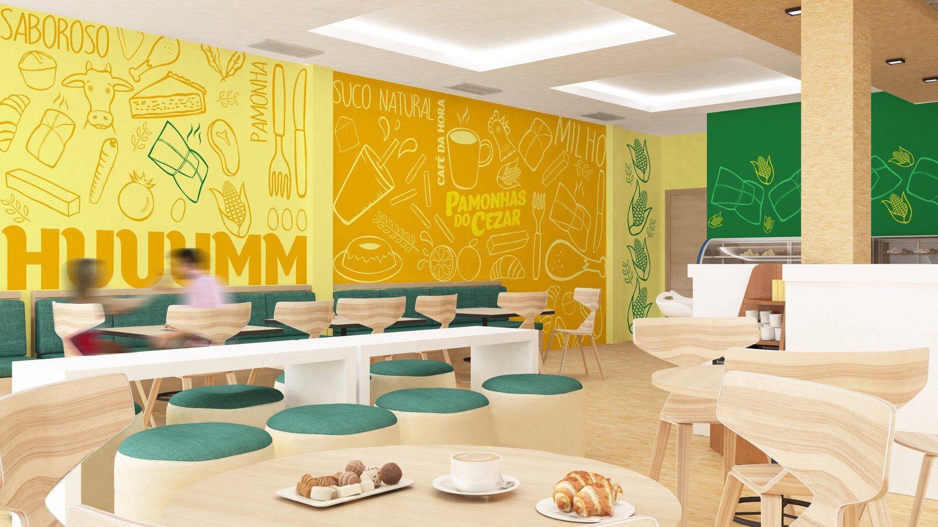 Interior de um café em amarelo e verde vibrante. Conta com longas mesas brancas com assentos azul-petróleo, cadeiras de madeira e comida nas mesas.