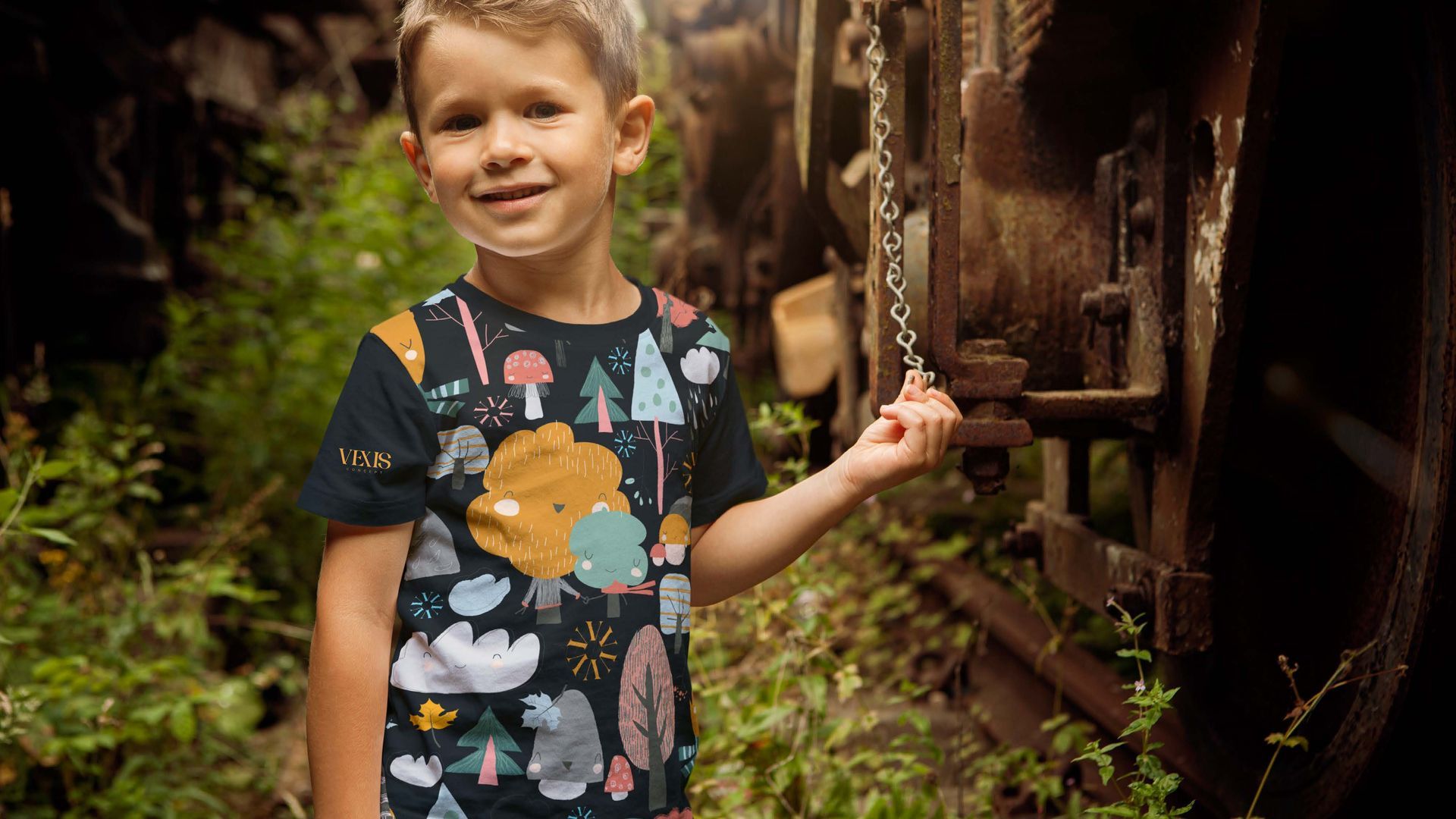 Menino sorrindo, vestindo uma camisa com estampa de floresta, em pé ao lado de uma máquina enferrujada em uma área escura e coberta de mato.
