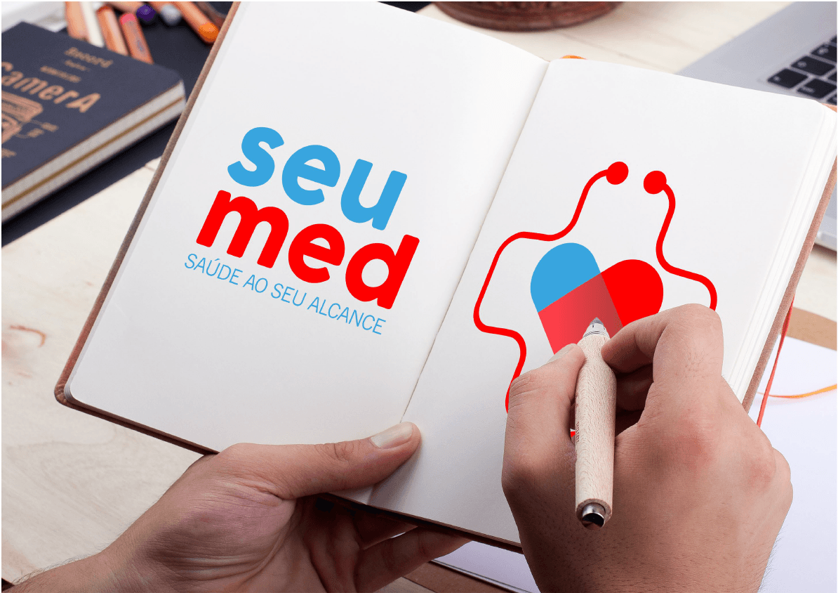 Pessoa desenhando um desenho com tema médico em um caderno. O caderno apresenta as palavras