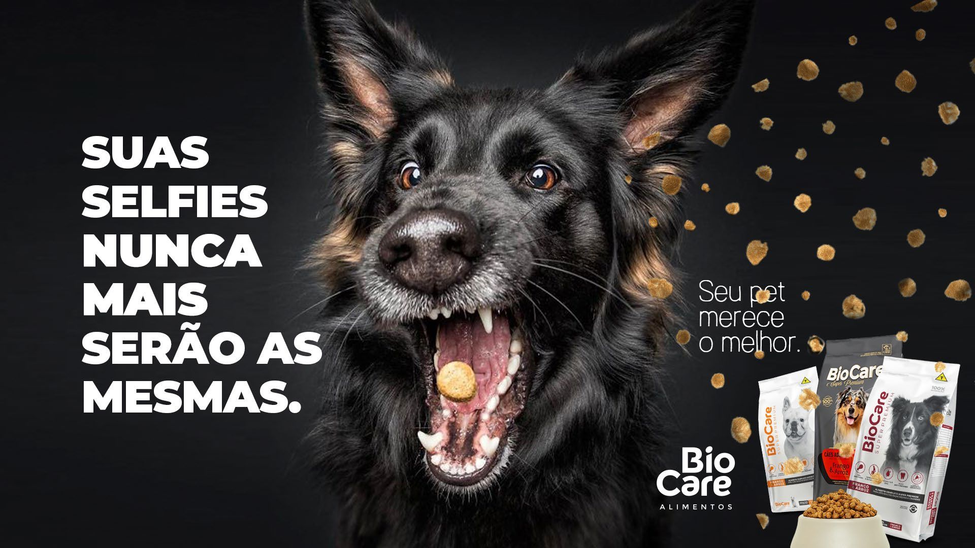 Um cachorro preto com a boca aberta está comendo uma guloseima.