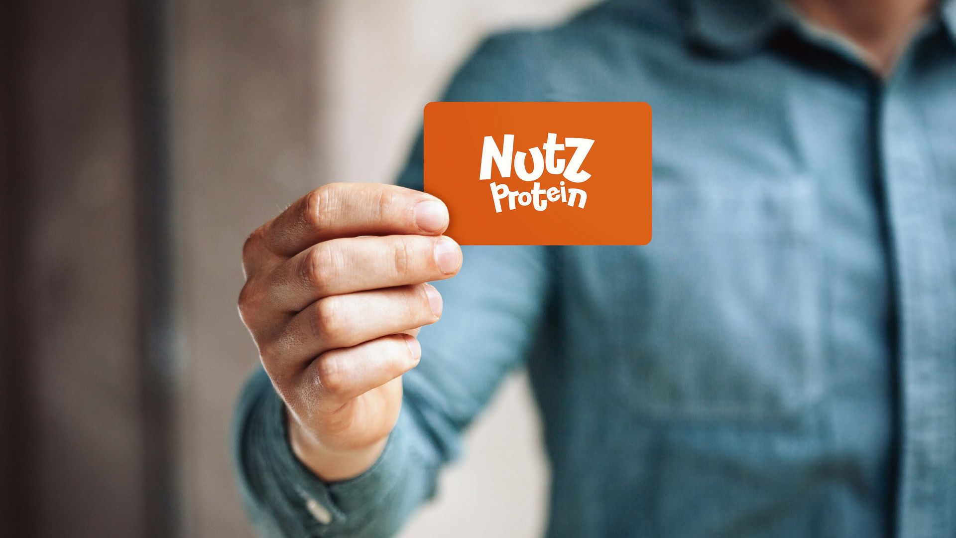 Pessoa de camisa azul segura um cartão de visita laranja da