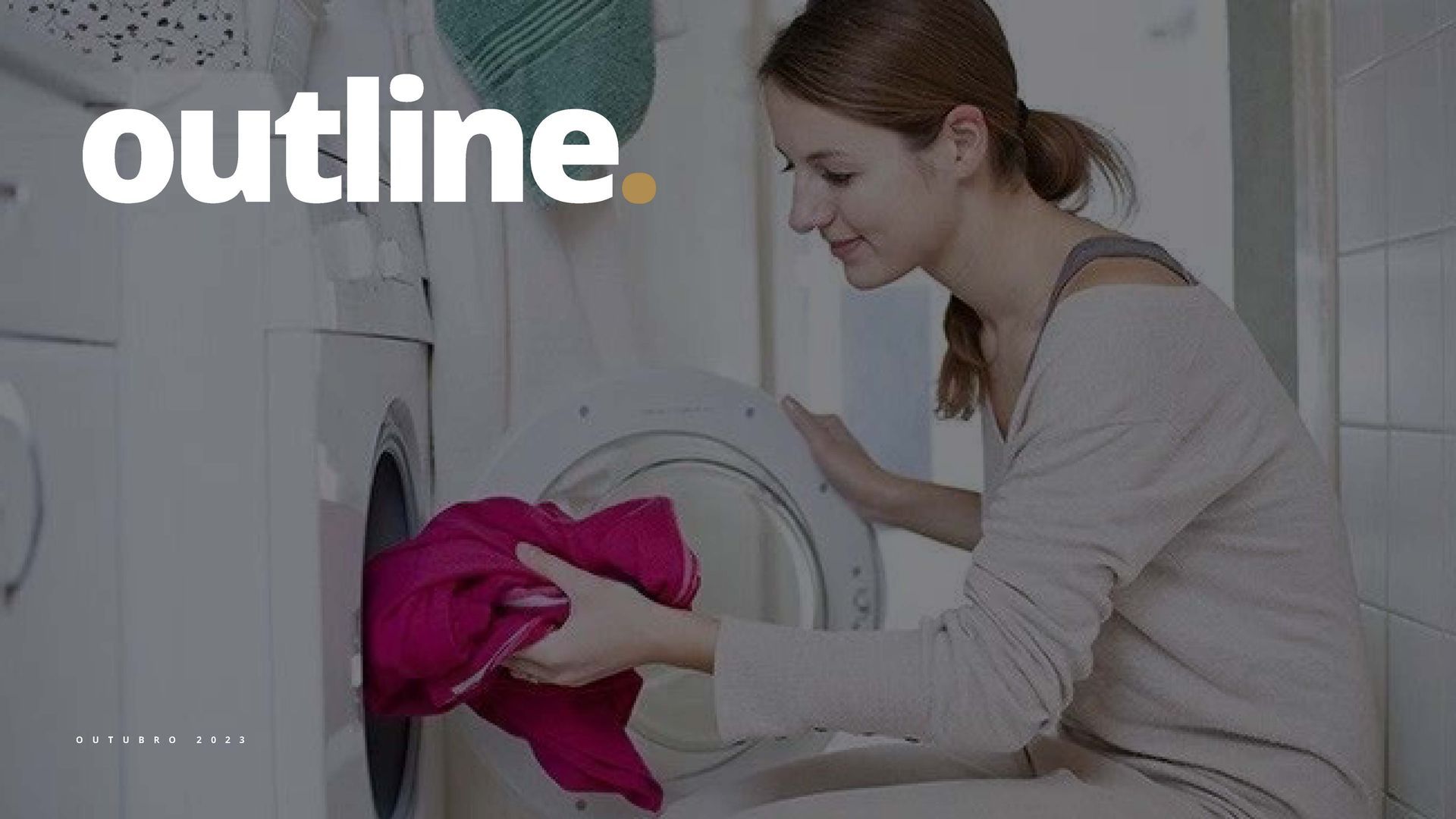 Mulher colocando roupas na máquina de lavar no banheiro. Ela veste uma camisa de mangas compridas e sorri.