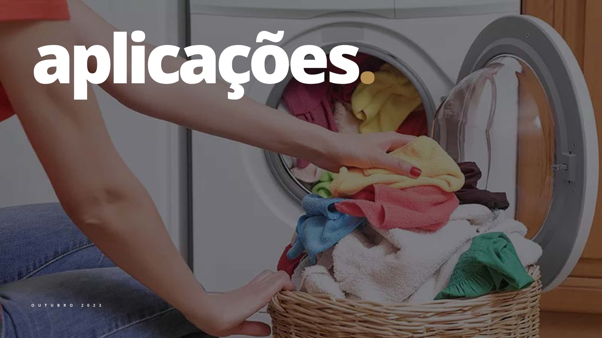 Uma pessoa colocando roupas na máquina de lavar. Um cesto de roupa suja está à sua frente.