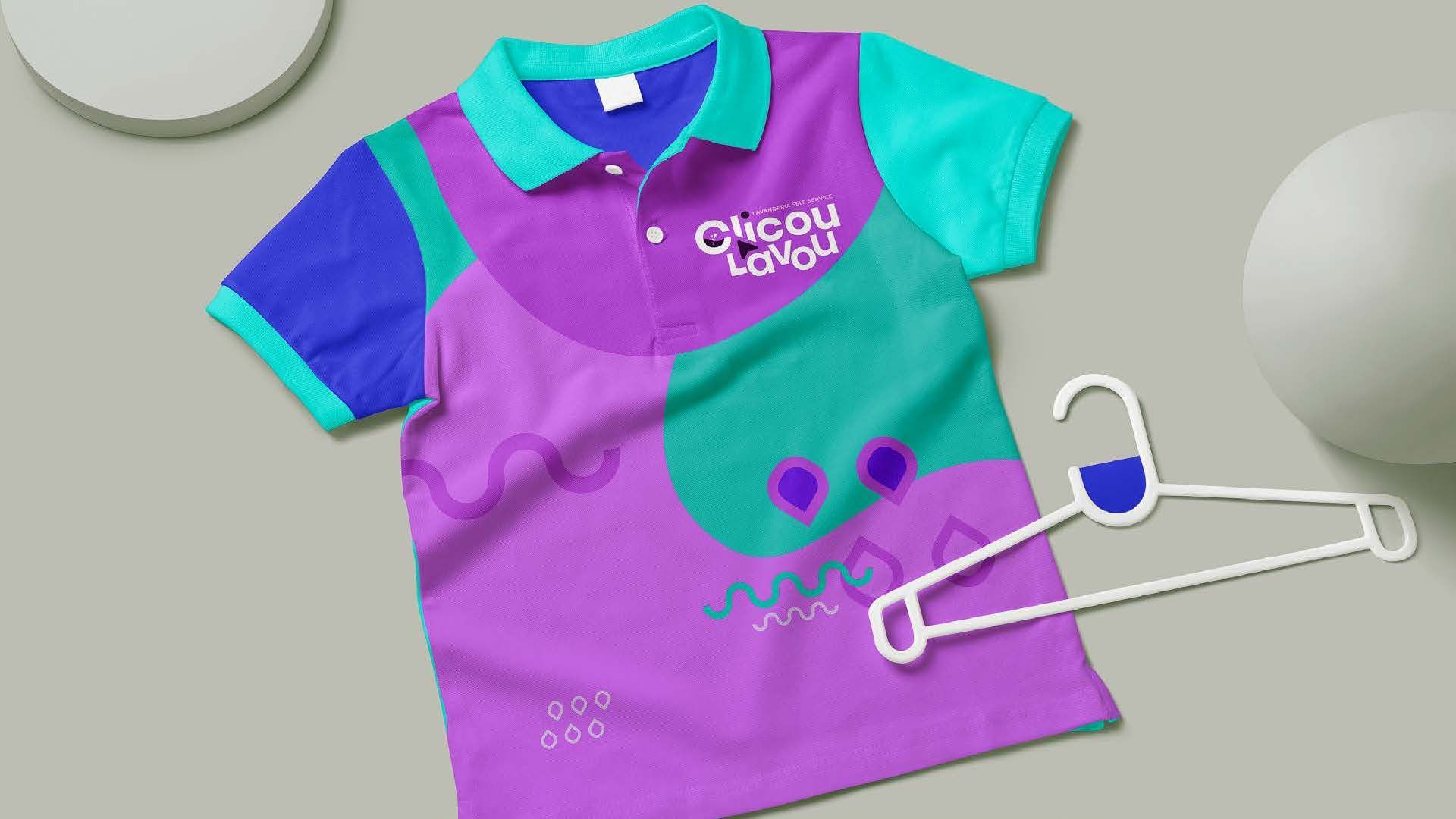 Uma camisa polo colorida com um design roxo, azul-petróleo e azul, a camisa está ao lado de um cabide branco.