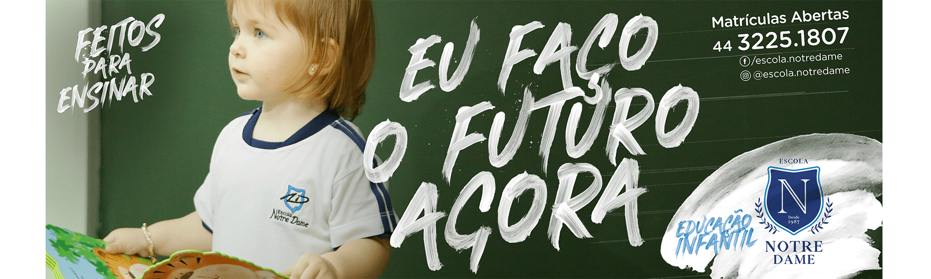 Uma criança segura um livro em frente a um quadro negro que diz eu faco o futuro agora
