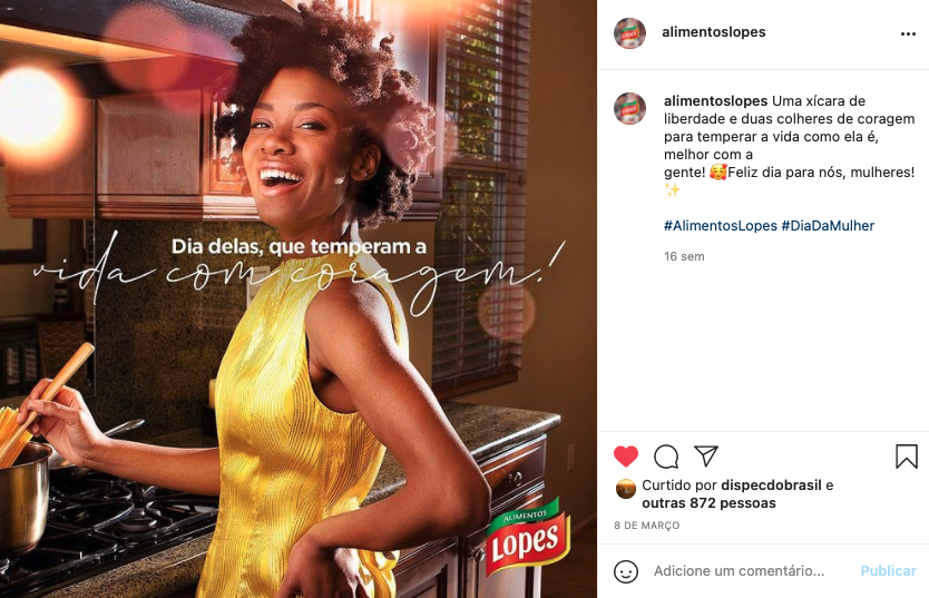 Uma mulher de vestido amarelo está cozinhando em uma cozinha.