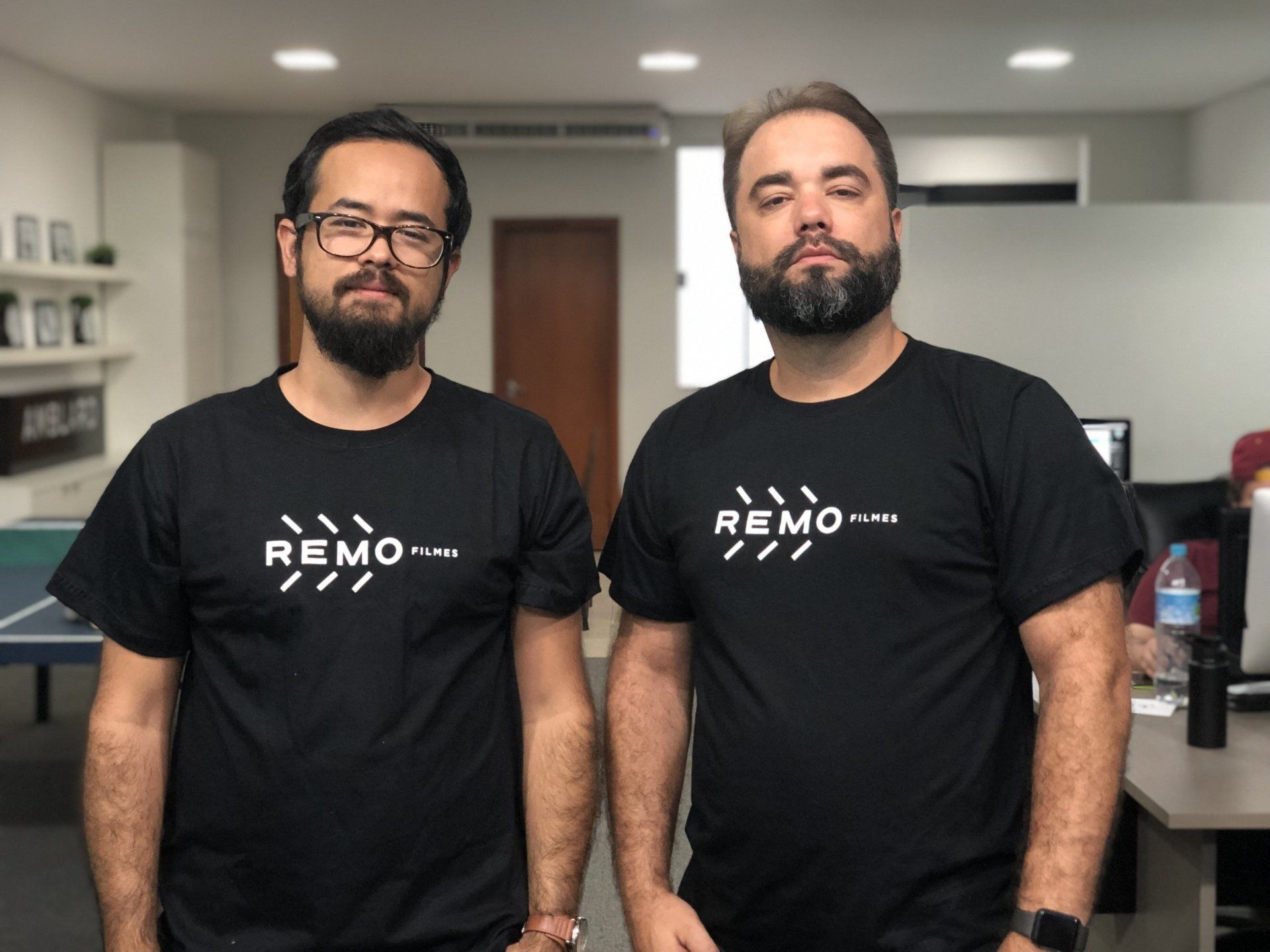 Dois homens vestindo camisetas pretas com a inscrição