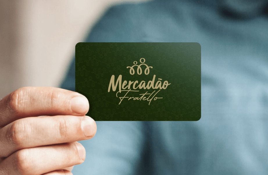Pessoa segurando um cartão de visita verde com o logotipo dourado