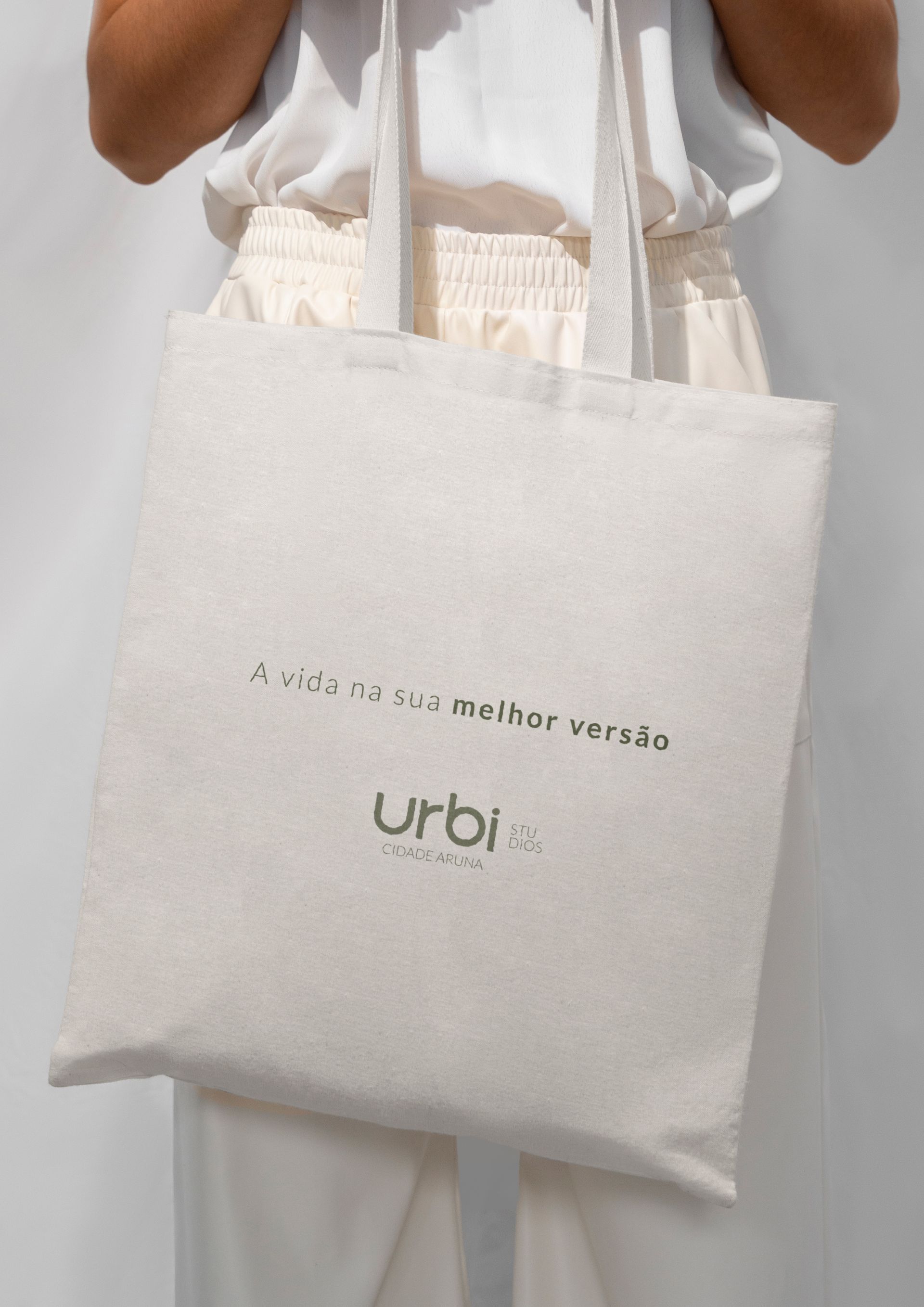 Uma pessoa segura uma sacola branca com o texto verde