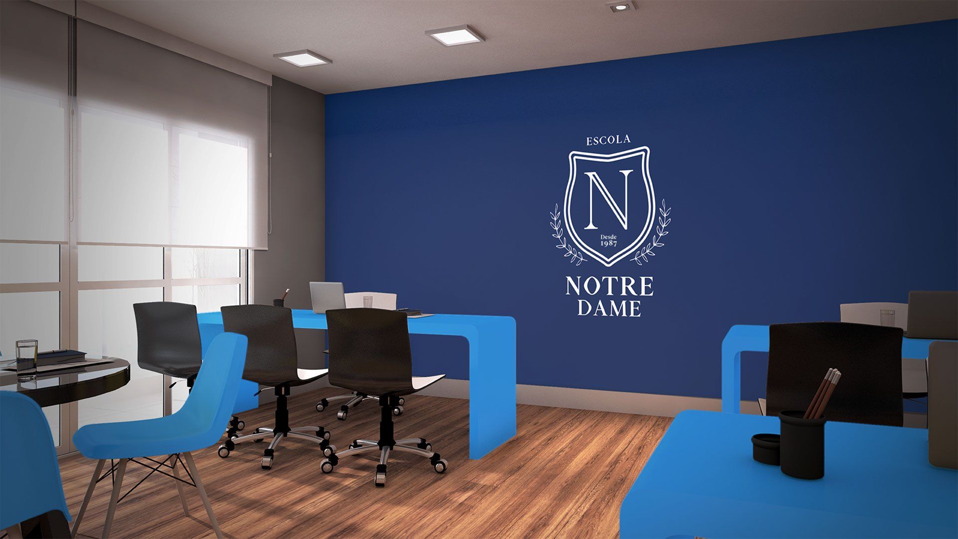 Um espaço de escritórios da Notre Dame bem iluminado com detalhes em azul. Uma parede azul exibe o logotipo da universidade, e mesas e cadeiras em vários tons de azul e preto.