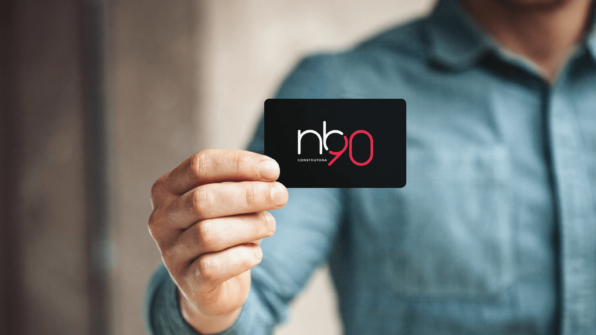 Pessoa segurando um cartão de visita preto com um logotipo branco e vermelho que diz