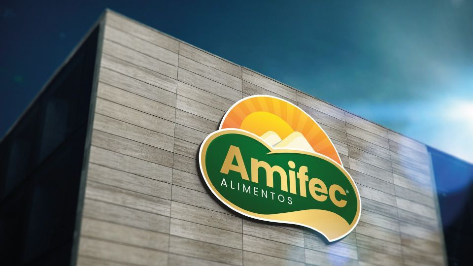 Logotipo da Amifec Alimentos na lateral de um prédio moderno; emblema verde, amarelo e laranja.