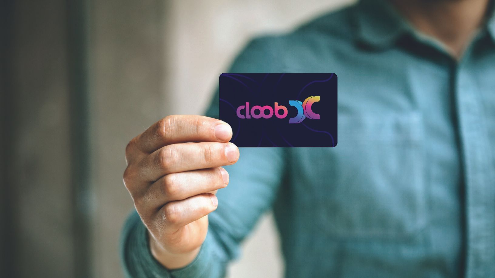 Uma pessoa com uma camisa azul-petróleo segura um cartão escuro com o logotipo