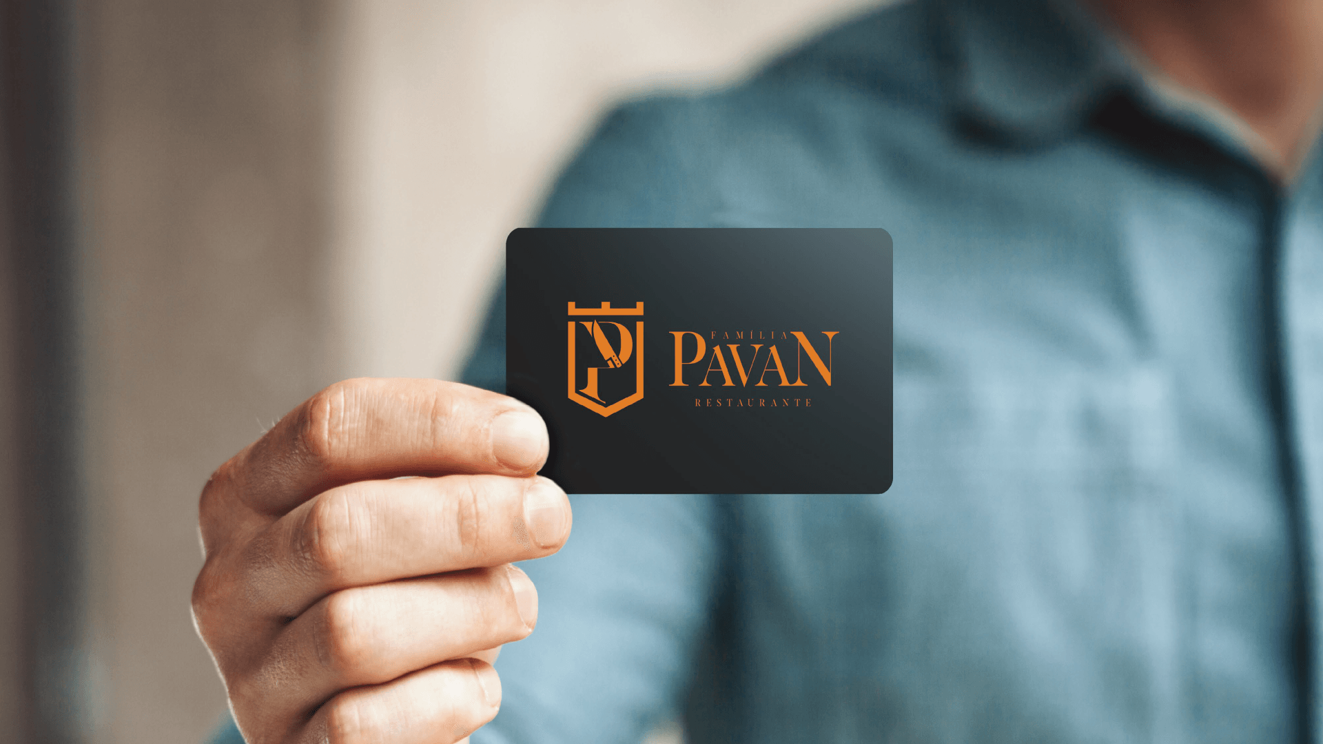 Pessoa segurando um cartão de visita preto com um logotipo dourado: