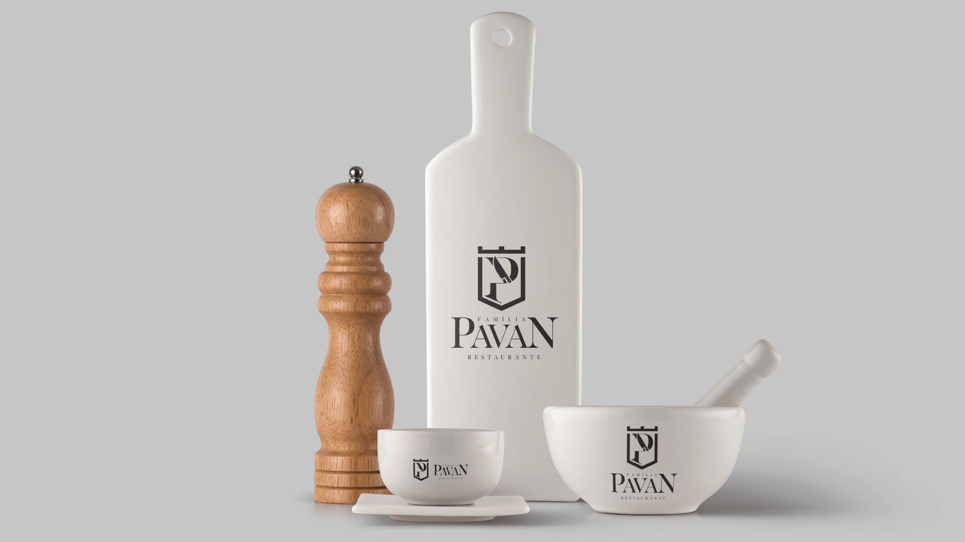 Moedor de pimenta de madeira, garrafa e tigela brancas, uma xícara pequena em um prato pequeno e um almofariz com pilão, todos com o logotipo