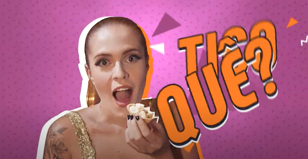 Mulher com a boca aberta, segurando comida, expressão de surpresa. Texto: