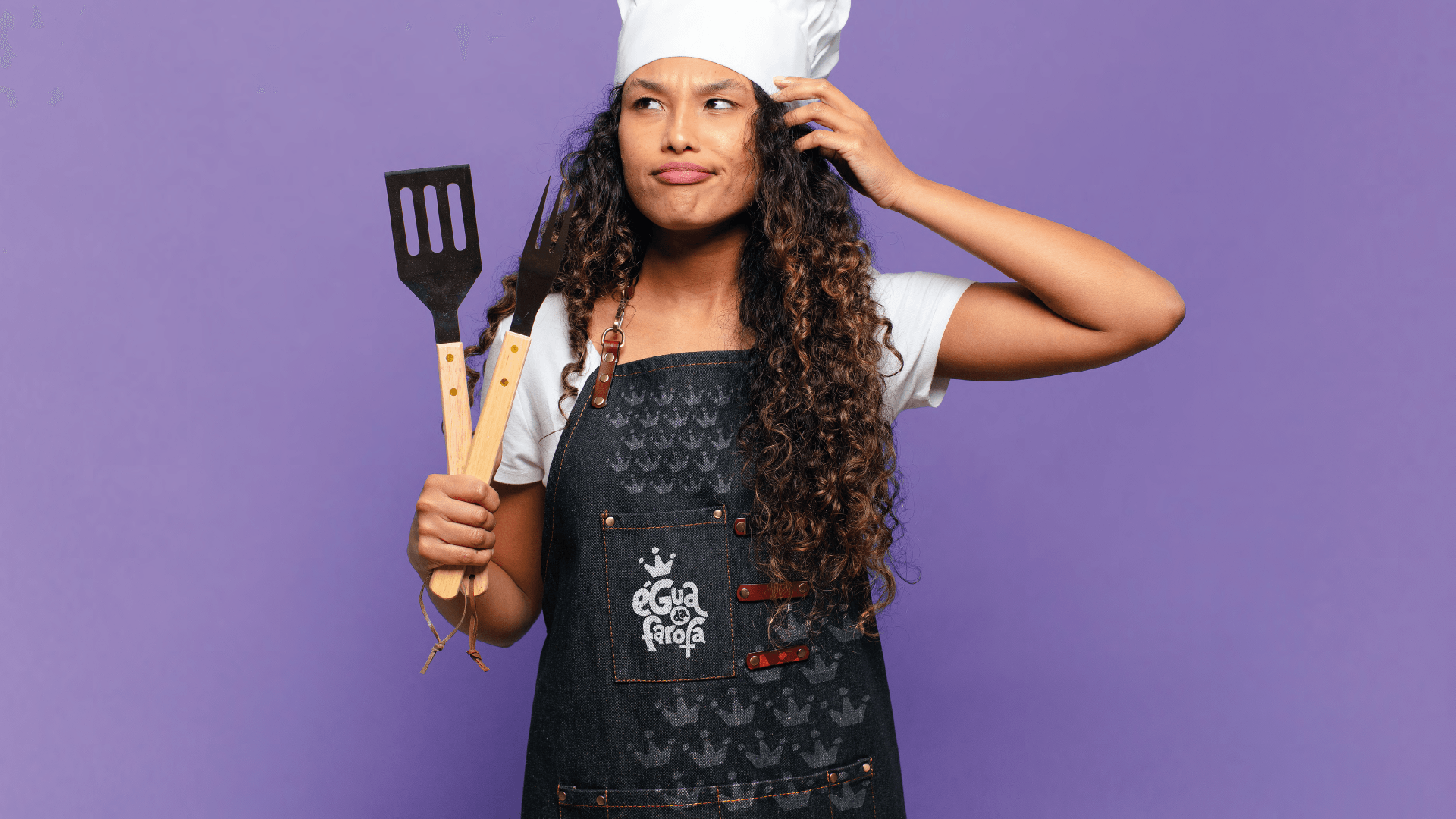 Uma mulher com chapéu e avental de chef está segurando uma espátula.