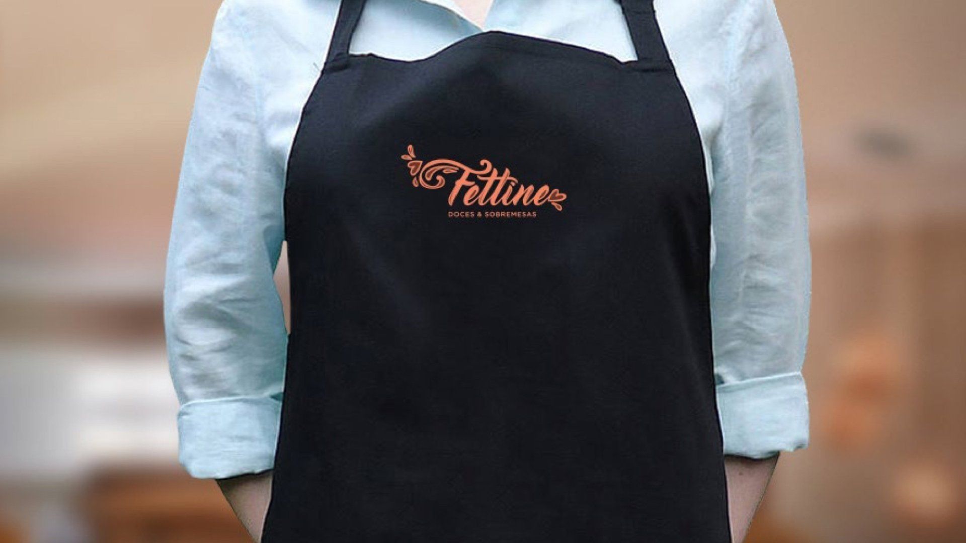 Uma mulher vestindo um avental preto com a palavra fitline bordada nele.