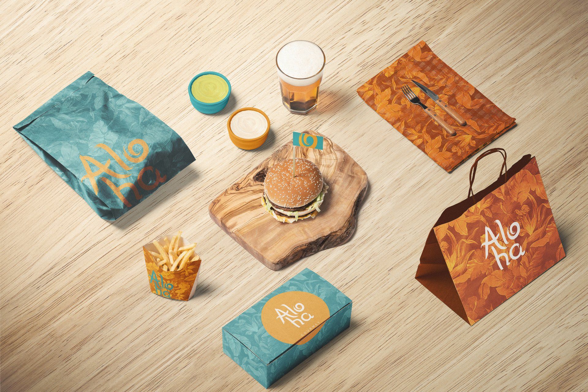 Uma mesa posta com recipientes de comida para viagem Aloha, um hambúrguer em uma tábua de madeira, batatas fritas, molhos e uma bebida.