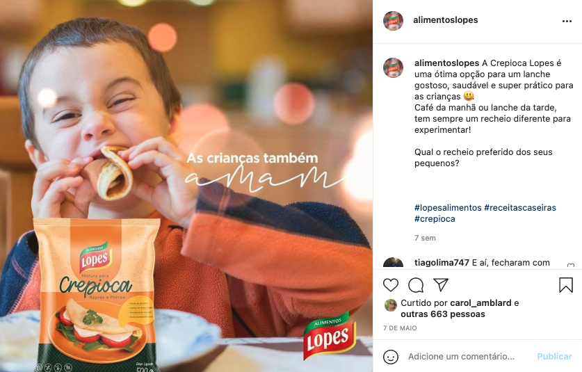 Um menino está comendo um sanduíche ao lado de um saco de comida.