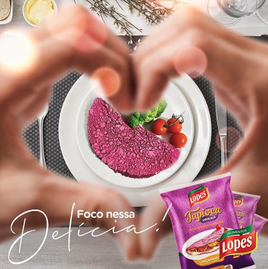 Uma pessoa fazendo um formato de coração com as mãos sobre um prato de comida