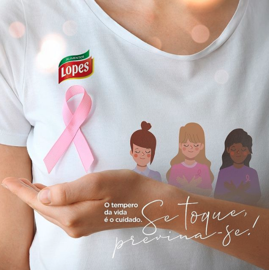 Uma mulher vestindo uma camiseta lopes segura uma fita rosa na mão