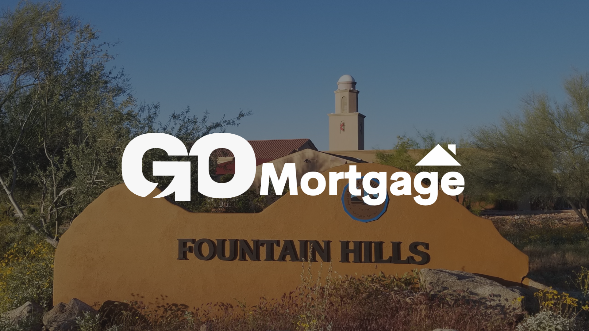 GO Mortgage logo over Fountain Hills sign, Arizona, with desert landscape and blue sky.