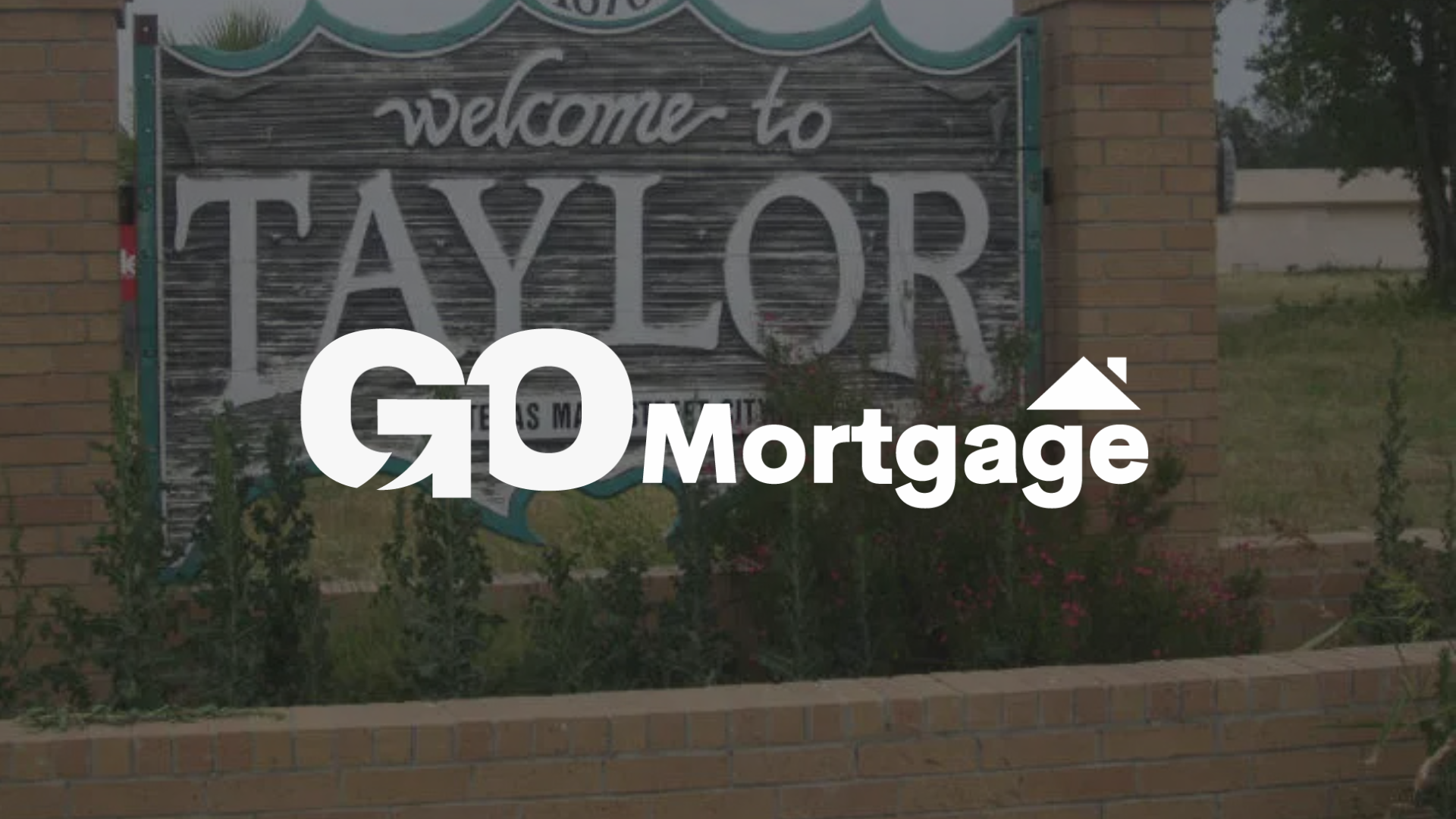 Sign welcoming people to Taylor, TX with Go Mortgage logo in front.