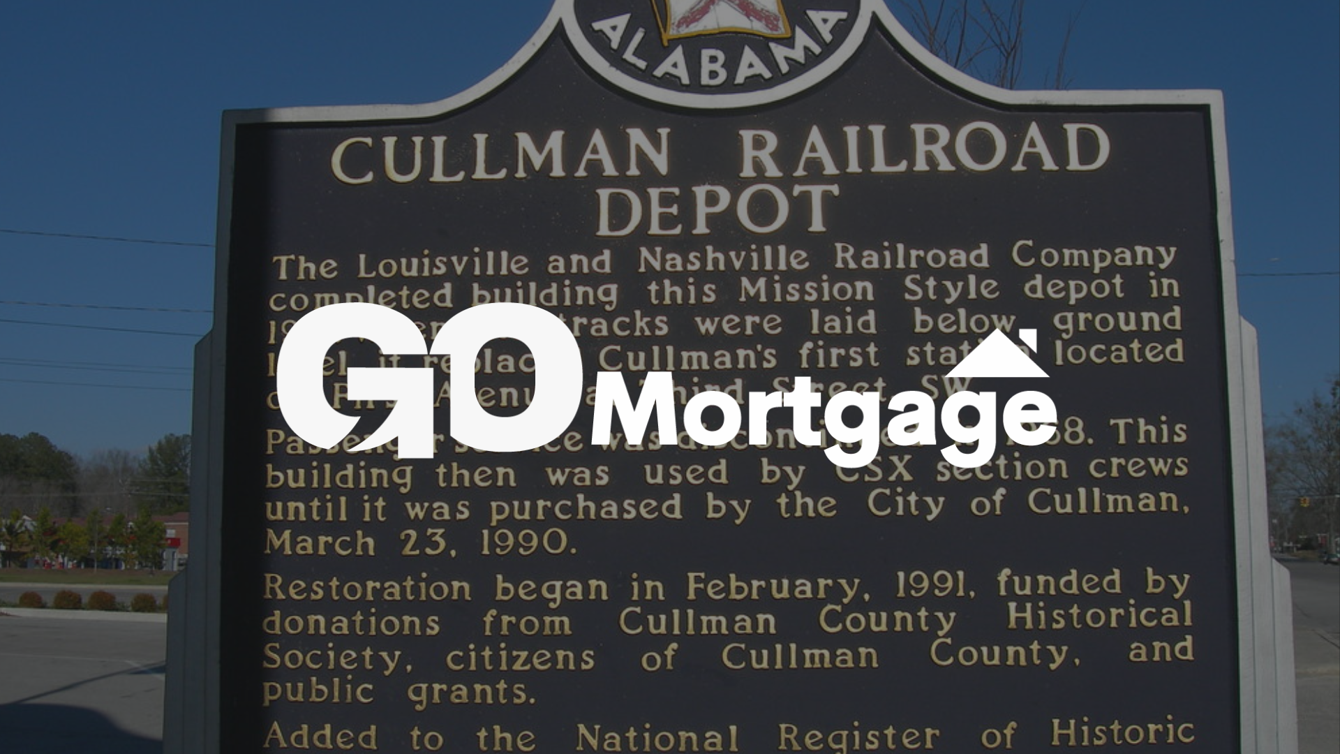 A sign that says ' cullman railroad depot ' on it with go mortgage logo on top