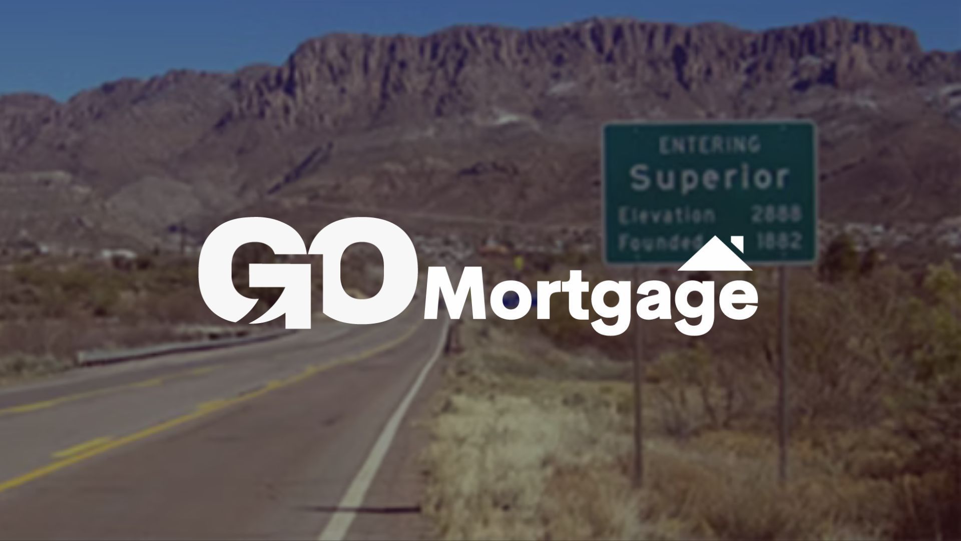 GO Mortgage logo on a road sign entering Superior, Arizona, with mountains in the background.
