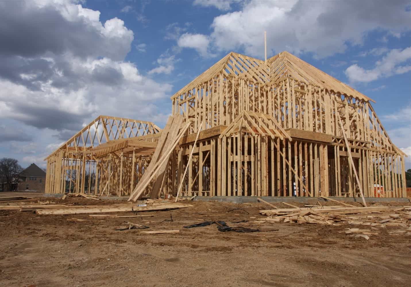 Wooden frame of a house under construction against a cloudy sky.