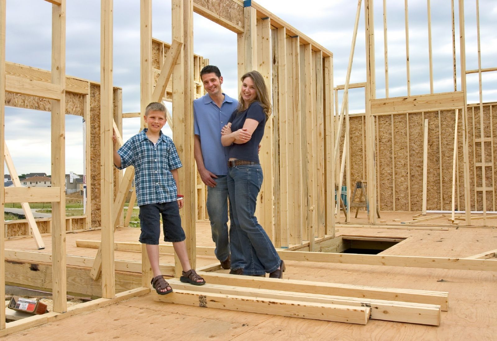 Family standing in the wooden frame of a house under construction.