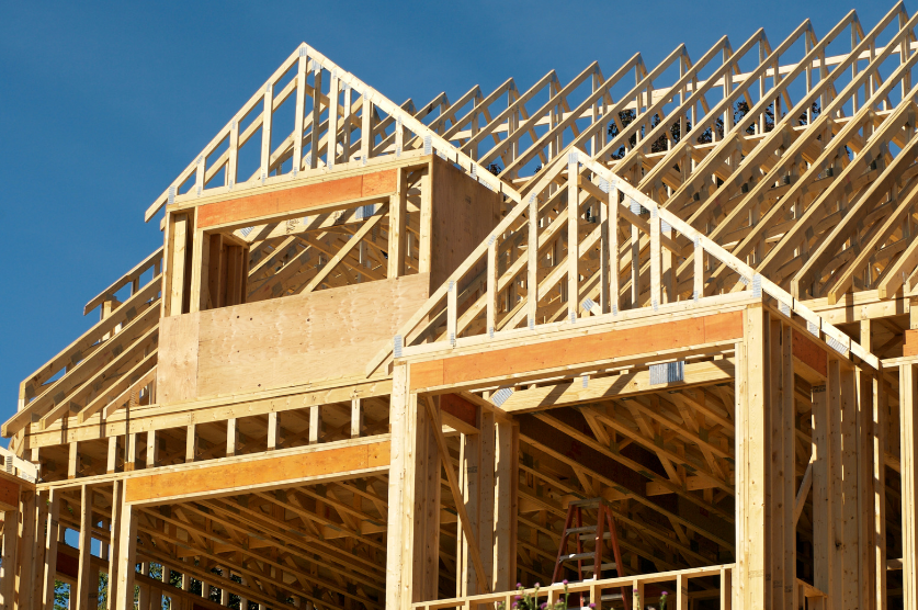 A large wooden house is being built with a blue sky in the background.