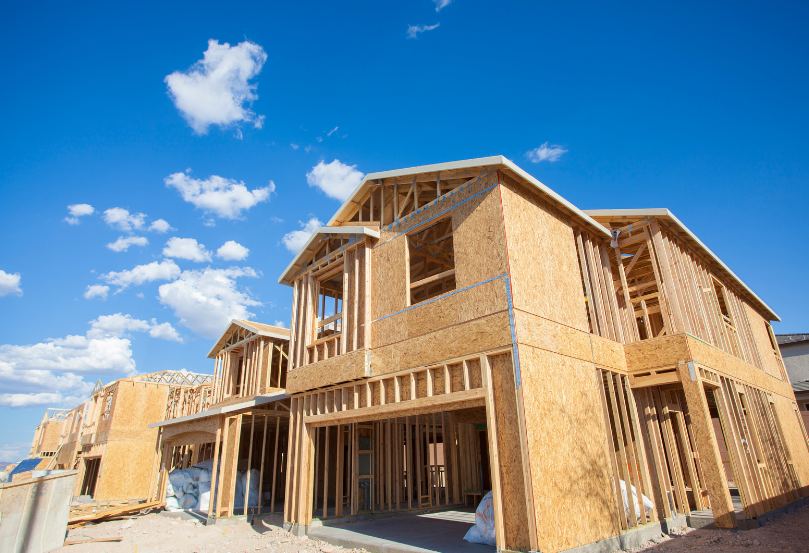 A large wooden house is being built on a sunny day.