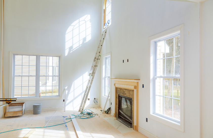 An empty living room with a fireplace and a ladder.