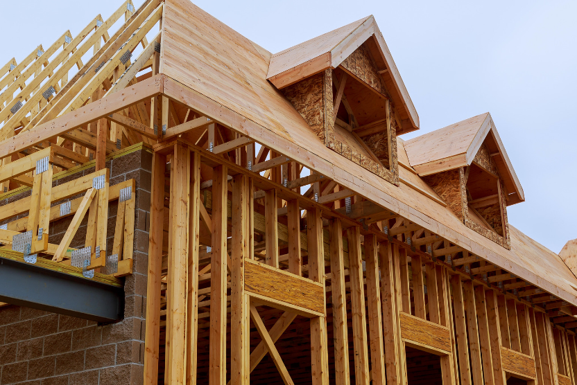 A house is being built with wooden beams and a roof.