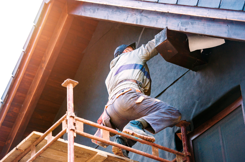 A man is standing on a scaffolding on top of a building.