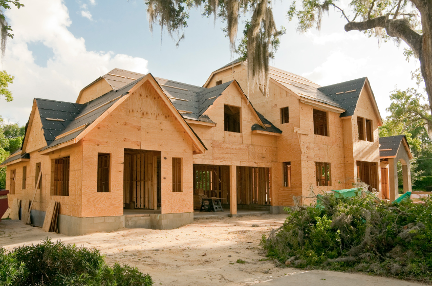 A large wooden house is being built in a rural area.