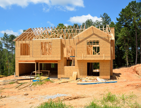 a large wooden house is being built in the middle of a dirt field .
