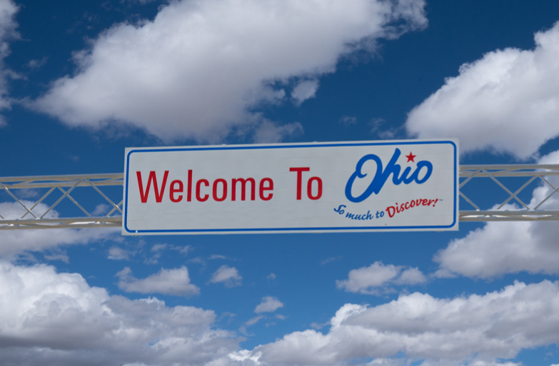 A welcome to ohio sign against a cloudy blue sky