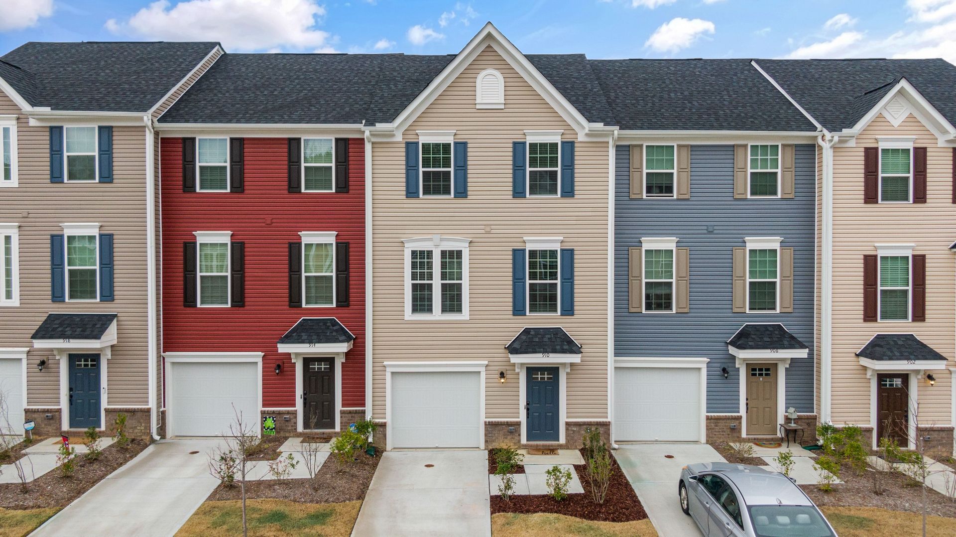 Row of modern townhouses with red, blue, and beige facades and small front porches